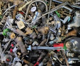 Haufen von gemischten Metallteilen, Rohren und Ventilen in verschiedenen Formen und Größen.