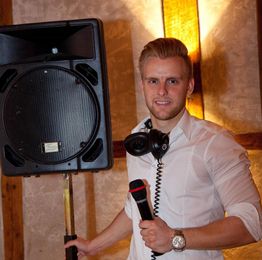 Ein Mann mit Mikrofon und Kopfhörern steht neben einem großen Lautsprecher.