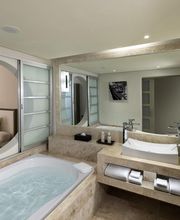 Baño moderno con bañera, lavabo, espejos grandes y puertas correderas hacia el dormitorio.