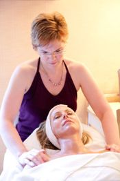 Frau erhält Gesichtsbehandlung in einem Spa, während eine andere Frau sie sanft massiert.