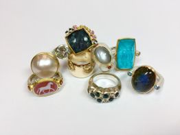 Verschiedene, bunte Ringe mit Edelsteinen auf weißem Hintergrund.
