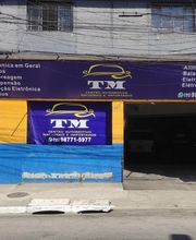 Fachada de oficina mecânica com banners azuis e amarelos destacando serviços automotivos.