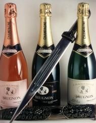 Drei Champagnerflaschen hinter einem Degen auf einem Tisch.