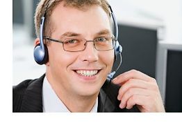 Ein lächelnder Mann mit Brille trägt ein Headset im Büro.