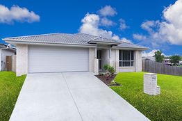 Single-story white brick house with a two-car garage and a well-kept lawn under a blue sky.
