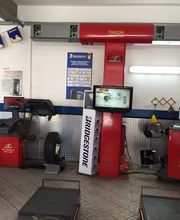 Officina con attrezzature per allineamento e bilanciamento pneumatici, monitor e logo Bridgestone.