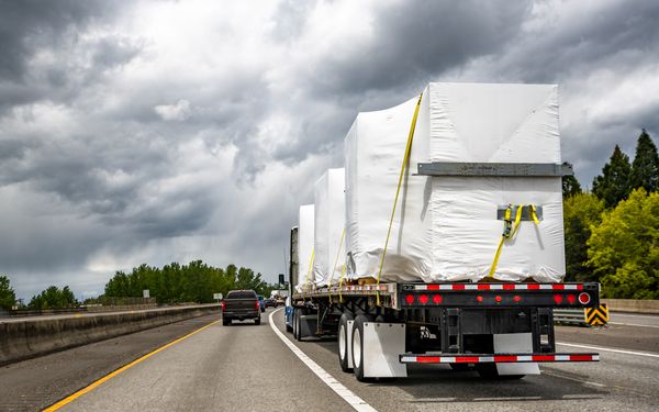 Es ist eine Autobahn abgebildet. Auf der rechten Spur fährt ein LKW, der eine schwere und vernünftig gesicherte Ladung transportiert. Links daneben fährt ein PKW.