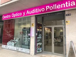 Tienda "Centro Óptico y Auditivo Pollentia" con escaparate de gafas y puerta de cristal.