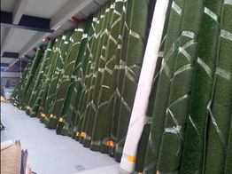 Opgerolde grasmatten staan rechtop in een opslagruimte.