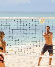 Persona jugando voleibol en la playa con el mar de fondo.