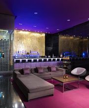 Bar moderno con sofá, sillas blancas y luces púrpuras. Decoración elegante y contemporánea.