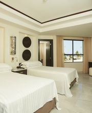 Habitación de hotel con dos camas, paredes claras y decoración moderna junto a una ventana.