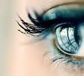 Nahaufnahme eines blauen Auges mit langen Wimpern und einem Reflexionseffekt im Auge.