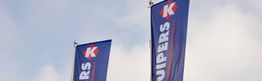 Twee blauwe Kuipers-vlaggen wapperen in de lucht tegen een bewolkte hemel.