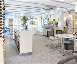 Optikergeschäft mit Brillenregalen, Beratungstisch und stufenlos zugänglichem, hellem Interieur.