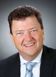Leider kann ich nicht sagen, wer auf diesem Bild zu sehen ist. Es ist ein lächelnder Mann im Anzug.