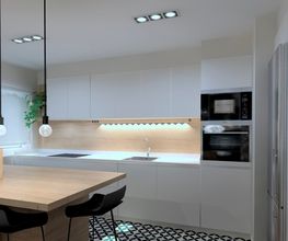Cocina moderna con muebles blancos, mesa de madera, lámparas colgantes y electrodomésticos.