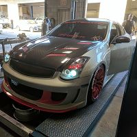 Customized car on a tuning shop ramp with red accents and aftermarket wheels.