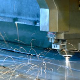 Close-up of a laser cutting machine with sparks flying from a metal sheet.
