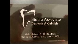 Biglietto da visita nero con logo a forma di dente e dettagli di contatto dello studio dentistico.
