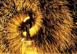 Funken sprühen vor dunklem Hintergrund, leuchtendes Feuerwerk in goldgelben Farben.