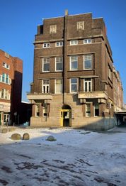 Bakstenen gebouw met sneeuw voor de deur, met een heldere blauwe lucht als achtergrond.
