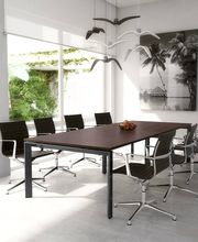 Sala de reuniones moderna con mesa marrón, sillas negras y cuadro de palmeras en la pared.