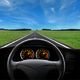 View from car dashboard of an empty road stretching into the horizon under a blue sky.