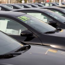 Row of black cars in a dealership lot, each featuring a sale sign in the window.