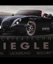 Schwarzes Auto vor grauem Himmel, Text: "Lackiertechnik Ziegler - Design, Lackierung, Beschriftung".