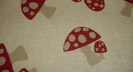 Beige Stoff mit roten Pilzen und weißen Punkten als Muster.
