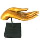 Goldene Handskulptur auf schwarzem Sockel, zeigt eine Hand mit ausgestreckten Fingern.