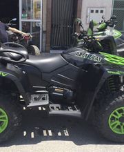 ATV negro con detalles verdes estacionado en la calle, marca y modelo visibles en el chasis.