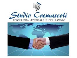 Stretta di mano davanti a una mappa del mondo con il logo "Studio Cremascoli".