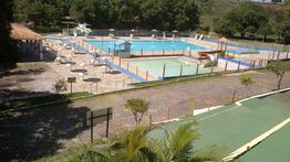 Vista de piscinas ao ar livre cercadas por árvores e espreguiçadeiras.