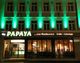 Gebäude bei Nacht, beleuchtet in Grün, mit Restaurant "Papaya" im Erdgeschoss.