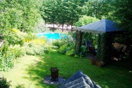 Garten mit Pool, Pavillon und vielen Bäumen; einladende, grüne Oase im Freien.