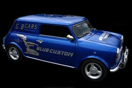 Blauer Mini mit "Blue Custom"-Aufschrift und Flügelmotiv auf schwarzem Hintergrund.