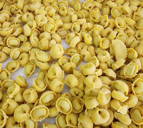 Pasta fresca all’uovo in vari formati su una superficie bianca leggermente infarinata.