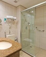 Banheiro moderno com pia marrom e box de vidro transparente.