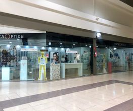 Una óptica en un centro comercial, con vitrinas y carteles en el exterior.