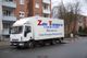 Ein weißer LKW der Firma "Zahn Transporte" steht auf einer Straße neben Wohngebäuden.
