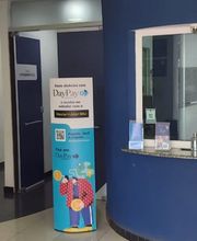 Corredor de clínica com parede azul, balcão de atendimento e cartaz promocional colorido.