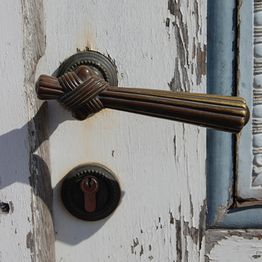 Antikes Türschloss mit schmiedeeisernem Griff und Patina auf einer alten Holztür.