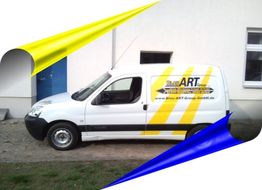 Weißer Lieferwagen mit gelbem und blauem Dekor vor einem weißen Gebäude.