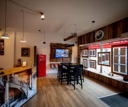 Gemütliches Café mit Holzmöbeln, rotem Kühlschrank und großen Fenstern zur Straße.