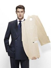 Ein Mann im Anzug hält eine Pappschablone eines Sakkos vor weißem Hintergrund.