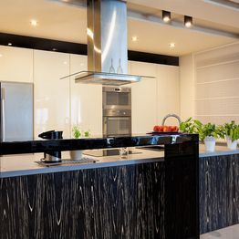 Modern kitchen with sleek black and white design, island counter, and stainless steel appliances.