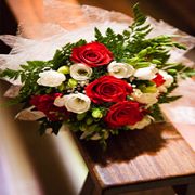 Bouquet of red and white roses with green leaves on a wooden bench.
