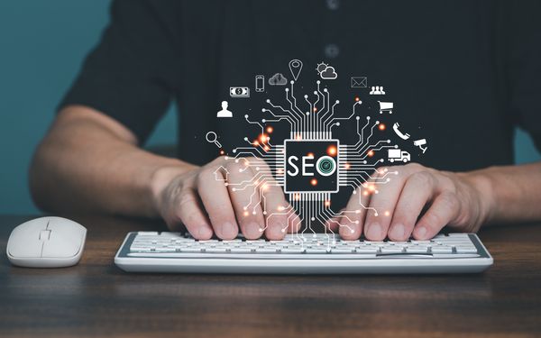 Eine Person tippt auf einer weißen Tastatur, darüber wurde eine symbolische Grafik für die Wichtigkeit von SEO-Strategien gelegt.